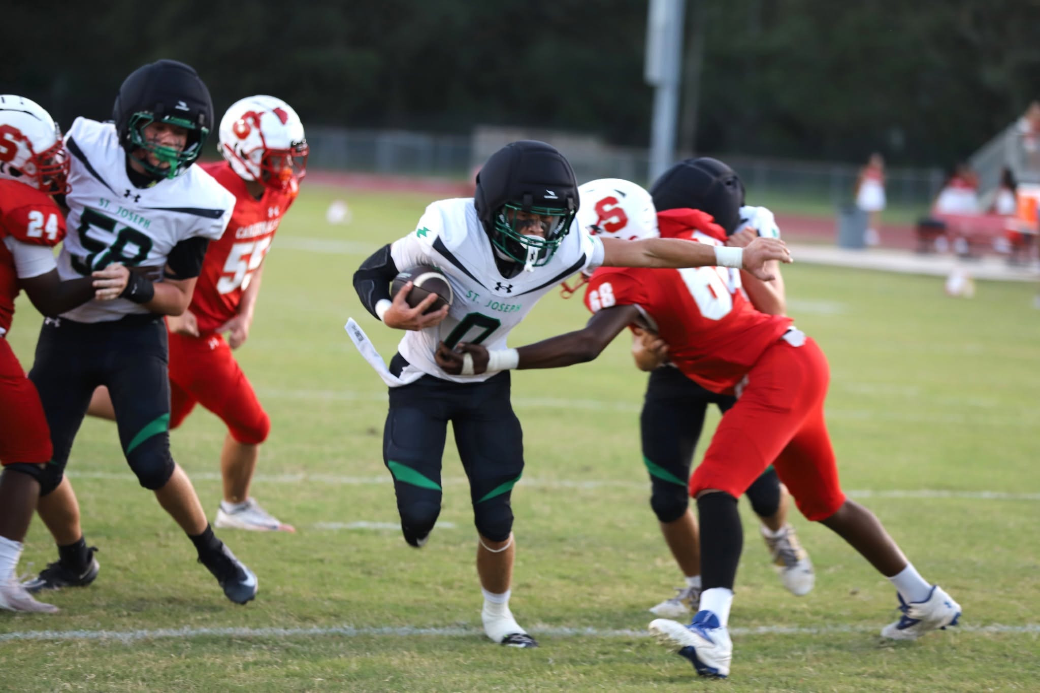 SJA Flashes football player in a white jersey carrying the ball during a game.